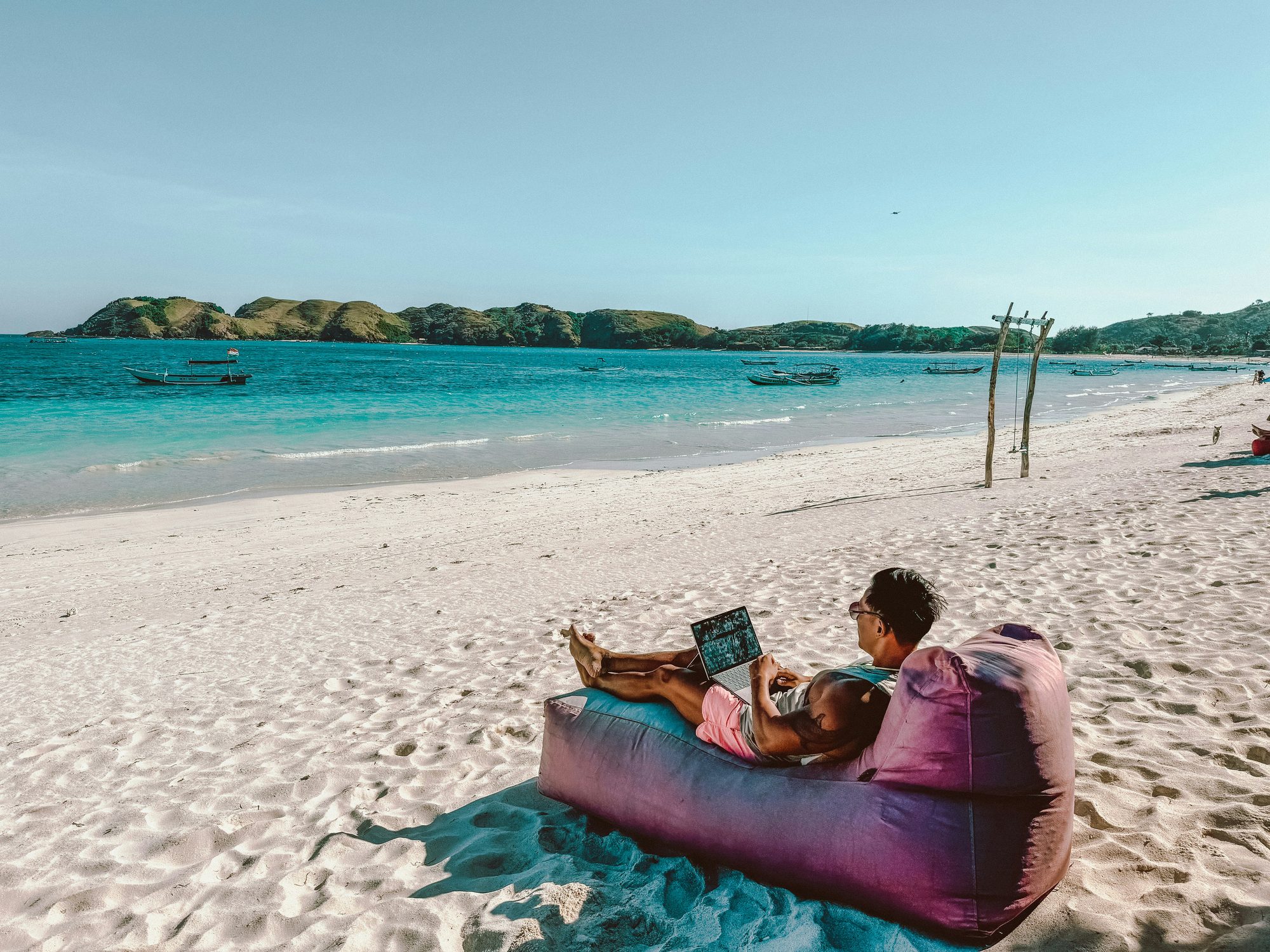 An agent working from a laptop on a beach